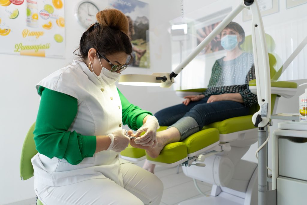 Podologin behandelt medizinisch den Fuß einer Patientin in der Praxis