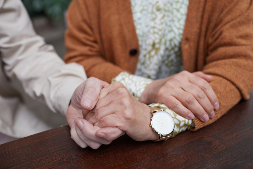 Jüngere Hand hält fürsorglich die Hand einer älteren Person